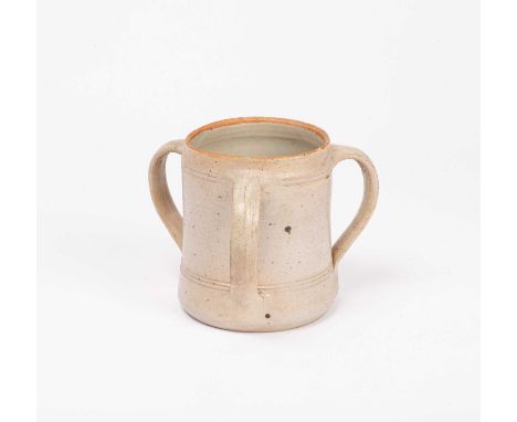 ARR Michael Cardew (1901-1983) a three-handled tyg in a cream glaze speckled with black and an orange rim, 15cm highA series 