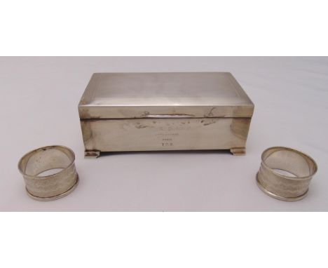 A hallmarked silver engine turned cigarette box and two hallmarked silver napkin rings