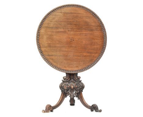An 18th century tripod table, the dished moulded top raised on a handsomely carved support formed as three dolphins on a scro