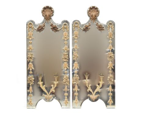 A pair of early 20th century shaped girandole mirrors, with applied carved limewood detail, shell cresting, over floral swags