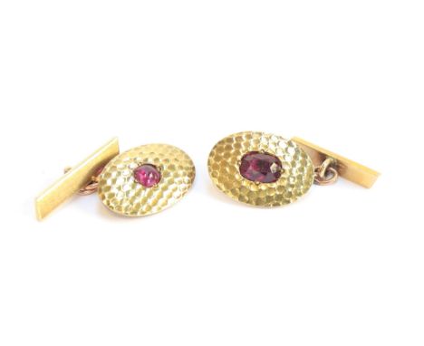 A matched pair of early 20th century French 18ct gold and ruby Art Deco cufflinks with a planished finish, one set with a cab