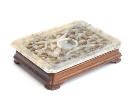 A Chinese grey jade cup stand, of rectangular panel form with canted corners, intricately carved in relief with dragons and b