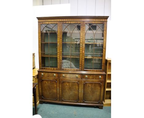 Georgian style mahogany display cabinet, the dentil pediment above three astragal glazed doors, the base with three frieze dr