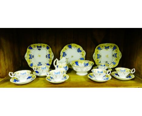 A 19th century porcelain tea set in the Rockingham style painted with blue fruit and vine pattern against a pale yellow and w