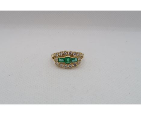 An 18ct yellow gold emerald and diamond ring - emeralds are a good colour, well matched with natural inclusions, surrounded b