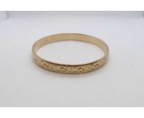 A 9ct yellow gold (hallmarked) bangle with chased decoration - Diameter 7cm - weight approx 44.1 grams 