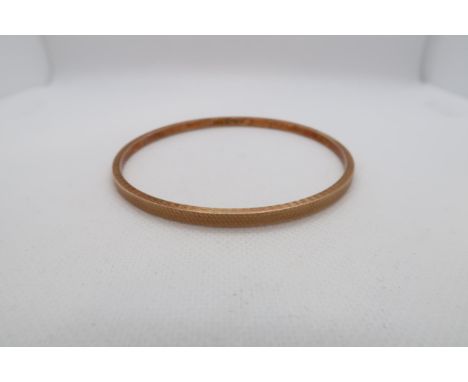 A 9ct gold (hallmarked) bangle with machined decoration - Diameter 7.5cm - approx weight 6.3 grams 
