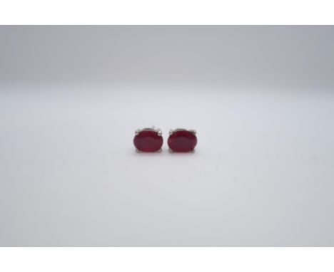 A pair of treated ruby studs set in silver 