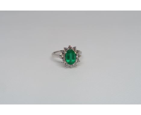 A good platinum (hallmarked) emerald and diamond cluster ring - the central oval emerald approx 1.3ct surrounded by 12 round 