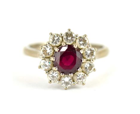 An 18ct white gold ring with claw set central ruby, within a border of ten claw set small brilliant cut diamonds, size L, app