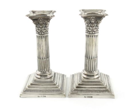 A pair of silver dwarf candlesticks, by The Harrison Brothers, Sheffield 1918, Corinthian column form, beaded borders, on rai