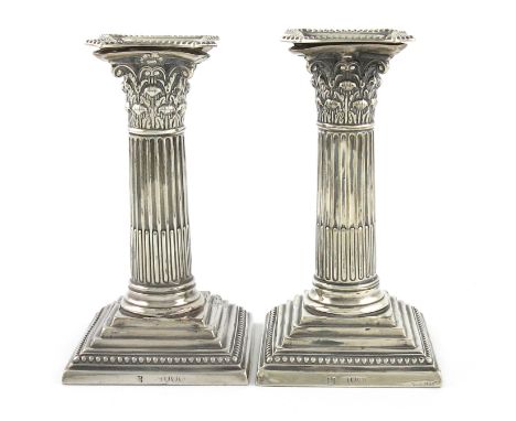 A pair of Victorian silver dwarf candlesticks, by E. Hutton, London 1889, Corinthian column form, beaded borders, on raised s
