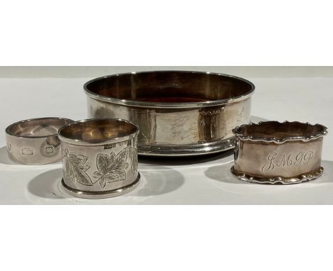 A silver wine bottle coaster, mahogany base, London 1998; a silver napkin ring, London 1975; other silver napkin rings (4) 