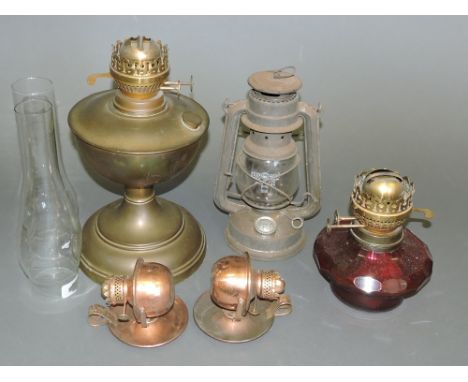 A brass oil lamp, together with another with a ruby glass oil reservoir two small copper lamps and a hurricane lantern, (5)