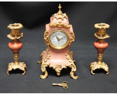 A pink marble and gilt-metal mounted clock garniture, in the French Rococo "style," comprising balloon and pair of candlestic