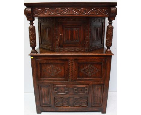 A large 18th century style oak court cupboard, c.1930s, with carved decoration, the top with linen fold panel door and column