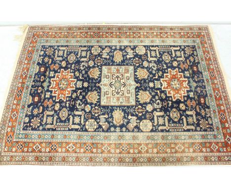 A blue ground Persian carpet, decorated with geometric designs surrounded by blue and red borders. 207 x 139 cm.