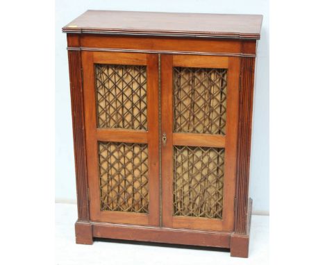 An early 20th century stained walnut two door pier cabinet, with a pair of gilt-metal trellis panelled doors enclosing a shel