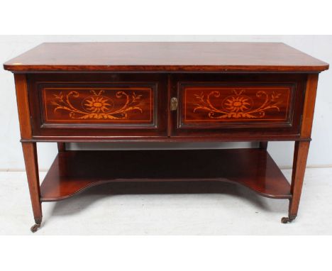 An Edwardian mahogany side table with two panel doors decorated with floral marquetry enclosing storage space above concave u