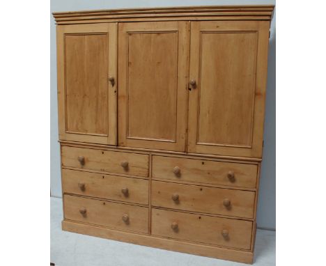 A 19th Century stripped and waxed pine triple wardrobe, with three panel doors above two side by side sets of three long grad