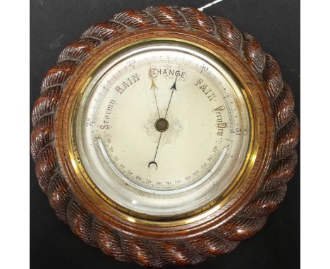 An early 20th century aneroid barometer, with silvered dial and thermometer, in stained oak rope-twist carved circular case, 