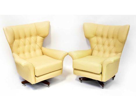 G-PLAN; a pair of Blofeld-style cream leather upholstered button pressed wing-back armchairs, with tilting swivel bases and c