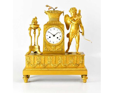An early 19th century French Empire ormolu figural mantel clock surmounted with cupid beside a torchère, the white enamelled 