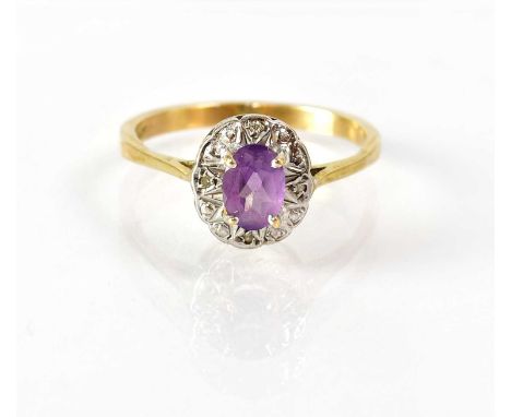 A 9ct gold ring set with an oval amethyst in a white gold engraved mount, stamped '9ct', size R, approx. 2.8g.
