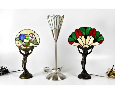 Two Tiffany-style leaded glass table lamps, each with a cast metal base in the form of an Art Deco lady with a fan-shaped sha
