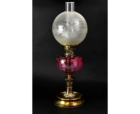 A Victorian paraffin lamp with frosted glass ball shade, funnel and cranberry glass font, with brass fittings, brass column a