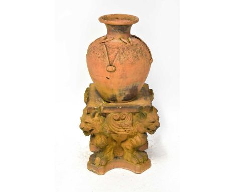 A terracotta amphora-type urn simulating stitched leather, height 38cm, on a square form moulded terracotta base with lion he