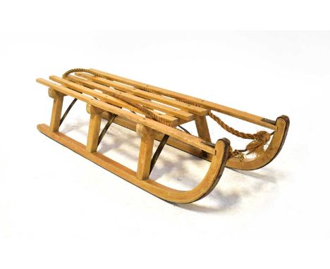 DAVOS; a vintage wooden sled, with slatted seat stamped with maker's details and metal covered runners, length 111cm.Conditio