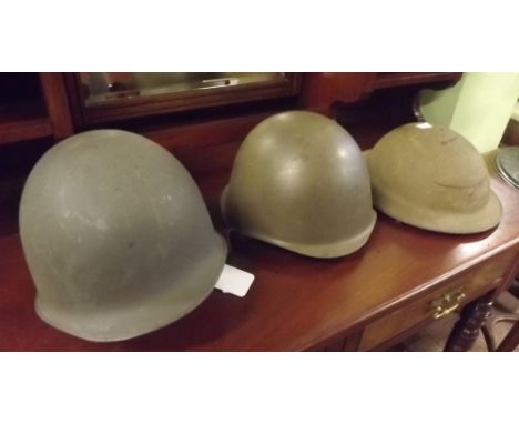 Two World War II American helmets and a British helmet. 