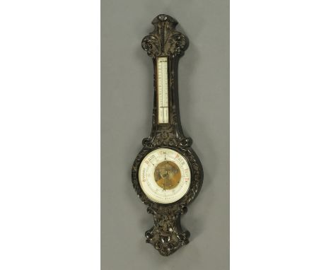 A late Victorian carved oak aneroid barometer, large form, with porcelain dial.  Height 112 cm. 