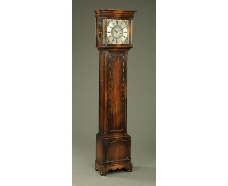 An oak longcase clock, with three-train spring driven movement, silvered brass square dial, long trunk door and raised on sho