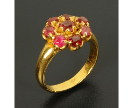 A gold coloured metal ring, with a cluster of ruby coloured stones, size K.