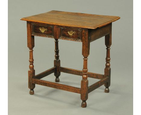 An antique oak side table, with three plank top with moulded edge, single frieze drawer and raised on turned legs united by s