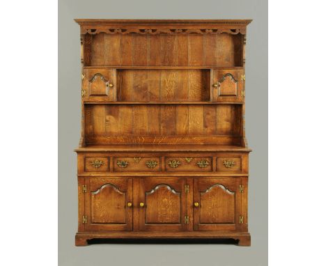 A reproduction oak dresser, with moulded dentil cornice above a series of shelves and cupboards, the base fitted with drawers