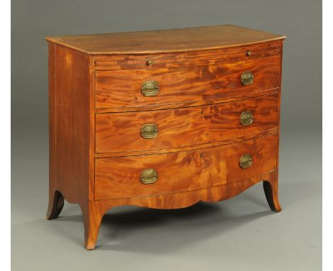 A George III mahogany bowfronted chest of drawers, with moulded edge, slide and three long graduated drawers with brass drop 