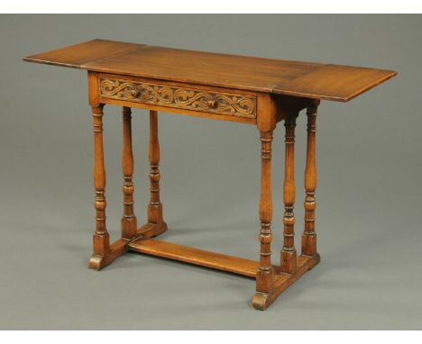 An Ipswich oak side table, twin drop flap, with carved drawer fronts and raised on turned supports and with low stretcher.  W