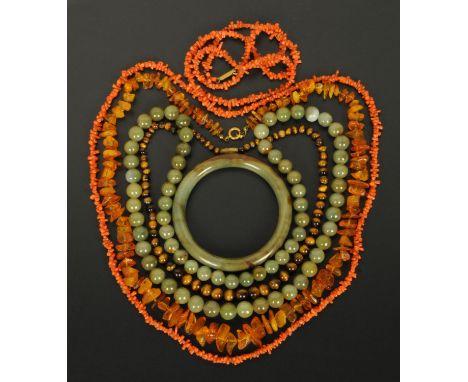 A jade bangle, strap of jade beads, coral necklace, tiger eye necklace and amber necklace.