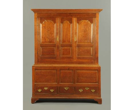 A George III oak press cupboard, with moulded cornice above a centre panel and pair of panelled cupboard doors, the base fitt