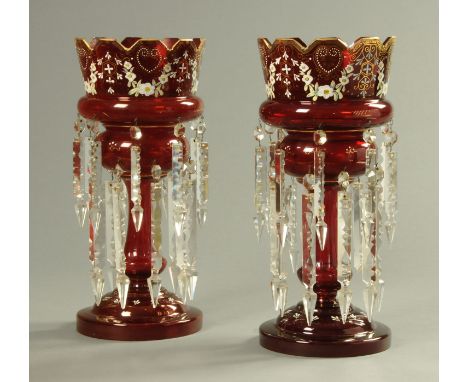A large pair of Victorian cranberry glass lustres, with gilding and foliate decoration and with two tiers of faceted lustre d