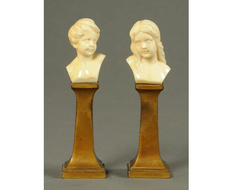 A pair of early 20th century ivory portrait busts, young boy and girl, each raised on a metal stand with stamp to rear.  Heig