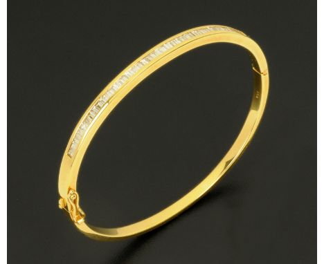 An 18 ct gold channel set baguette diamond bangle, stamped "750".  Internal dimensions 62 mm x 55 mm. 