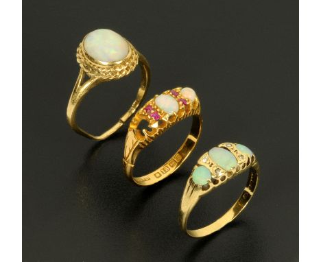 An 18 ct gold opal and ruby ring, (stone missing), and two other opal rings. 