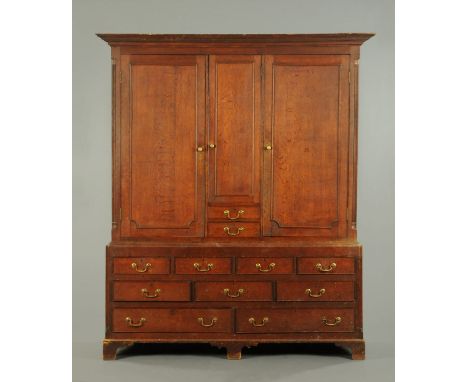 A George III oak housekeepers cupboard, with moulded cornice above a series of cupboards and drawers flanked by quarter colum