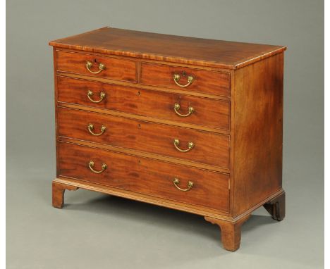 An early 19th century mahogany chest of drawers, with crossbanded top, two short and three long graduated drawers with brass 