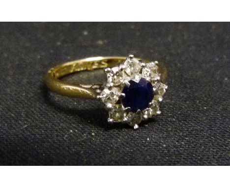 An 18ct. Gold Sapphire and Diamond Cluster Ring, with a central sapphire surrounded by diamonds within a pierced setting