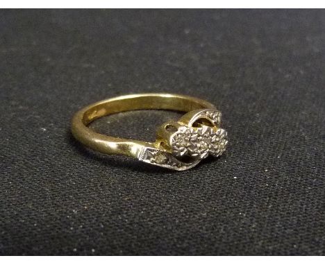 An 18ct. Gold and Platinum Set Diamond Cross-Over Ring, set with three diamonds and with diamond shoulders within a pierced s